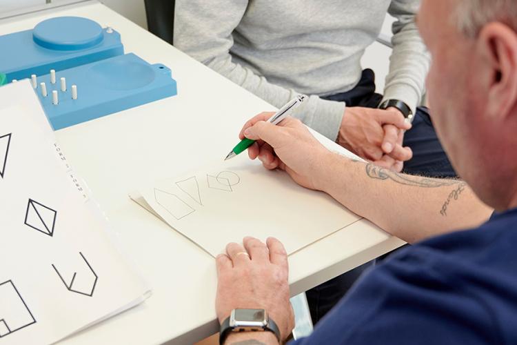 a patient performing a cognitive shape drawing test with paper and pen