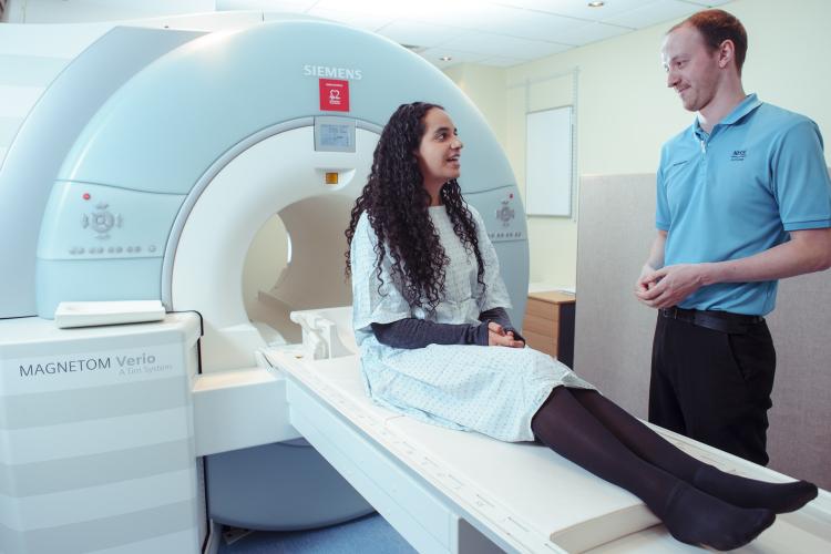 lady waiting to go into an MRI machine chatting to the radiographer