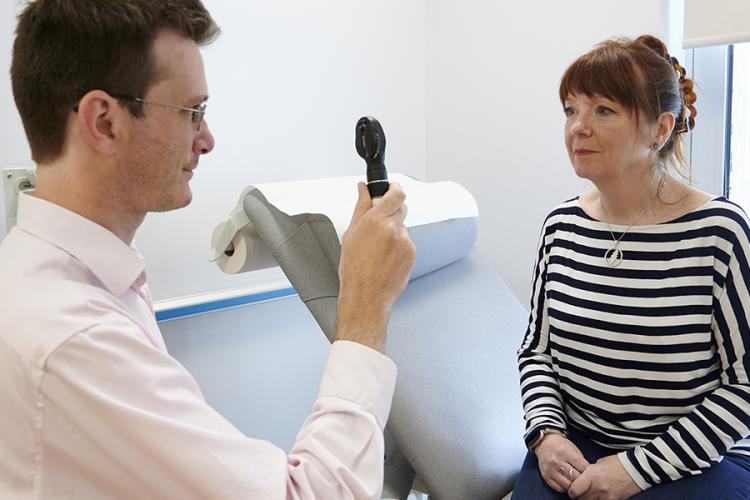 A doctor is performing an eye check on a patient in a clinic room
