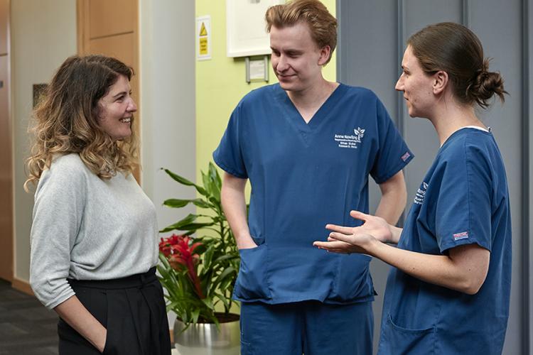 three researchers two in research scrub uniform talking in the reception area of the Anne Rowling Clinic building