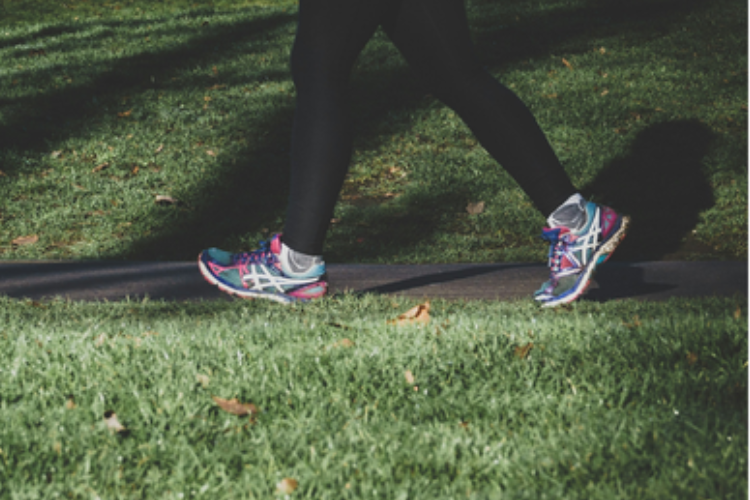 Person's feet and legs with trainers and running leggings jogging in a park