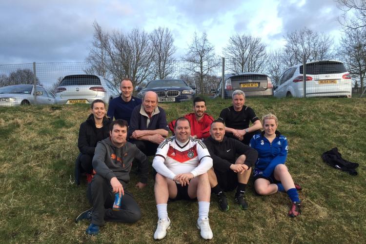 Jamie Smith and friends sat on a grass hill wearing sports clothes.
