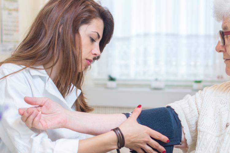 A doctor taking an older person's blood pressure using sphygmomanometer; a pressure meter