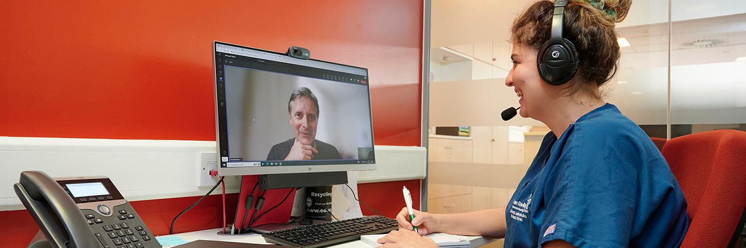 Researcher sitting in a confidential booth carrying out an online consultation with a trial participant.