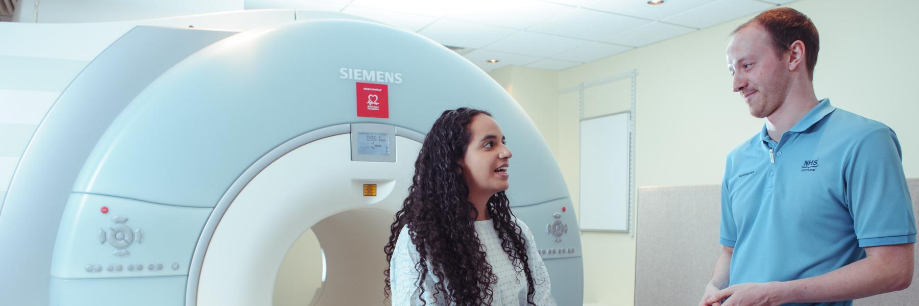 lady waiting to go into an MRI machine chatting to the radiographer