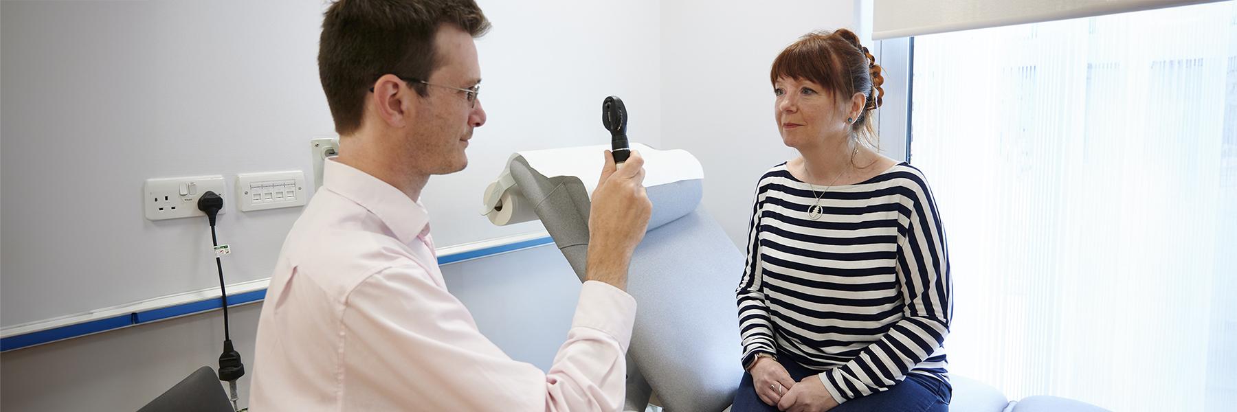 A doctor is performing an eye check on a patient in a clinic room