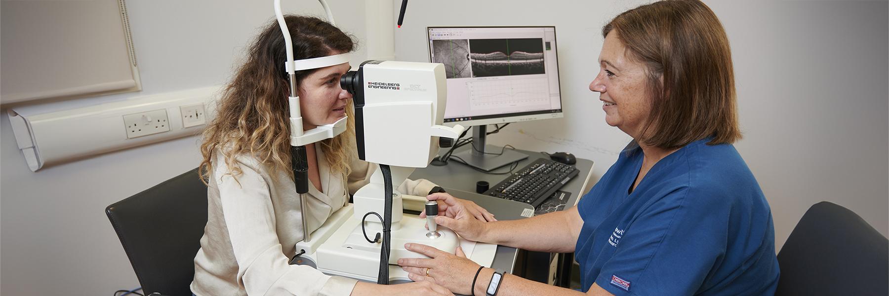 A researcher examining a study participant using opitcal coherence tomography equipment which images the back of a person's eye using reflected light,