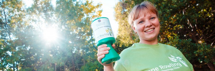 Young woman holding Anne Rowling Clinic collecting can smiling at camera