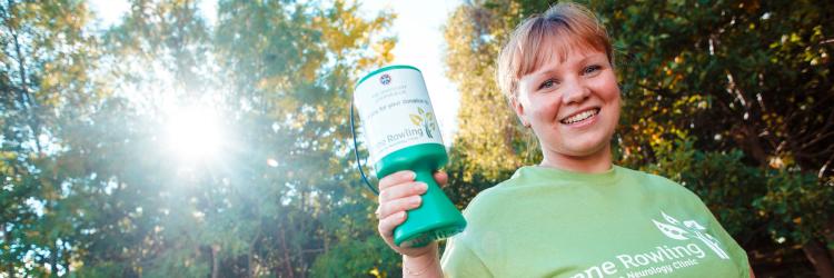 Young woman holding Anne Rowling Clinic collecting can smiling at camera